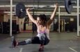 Kvinna utför en overhead squat med skivstång i en träningslokal
